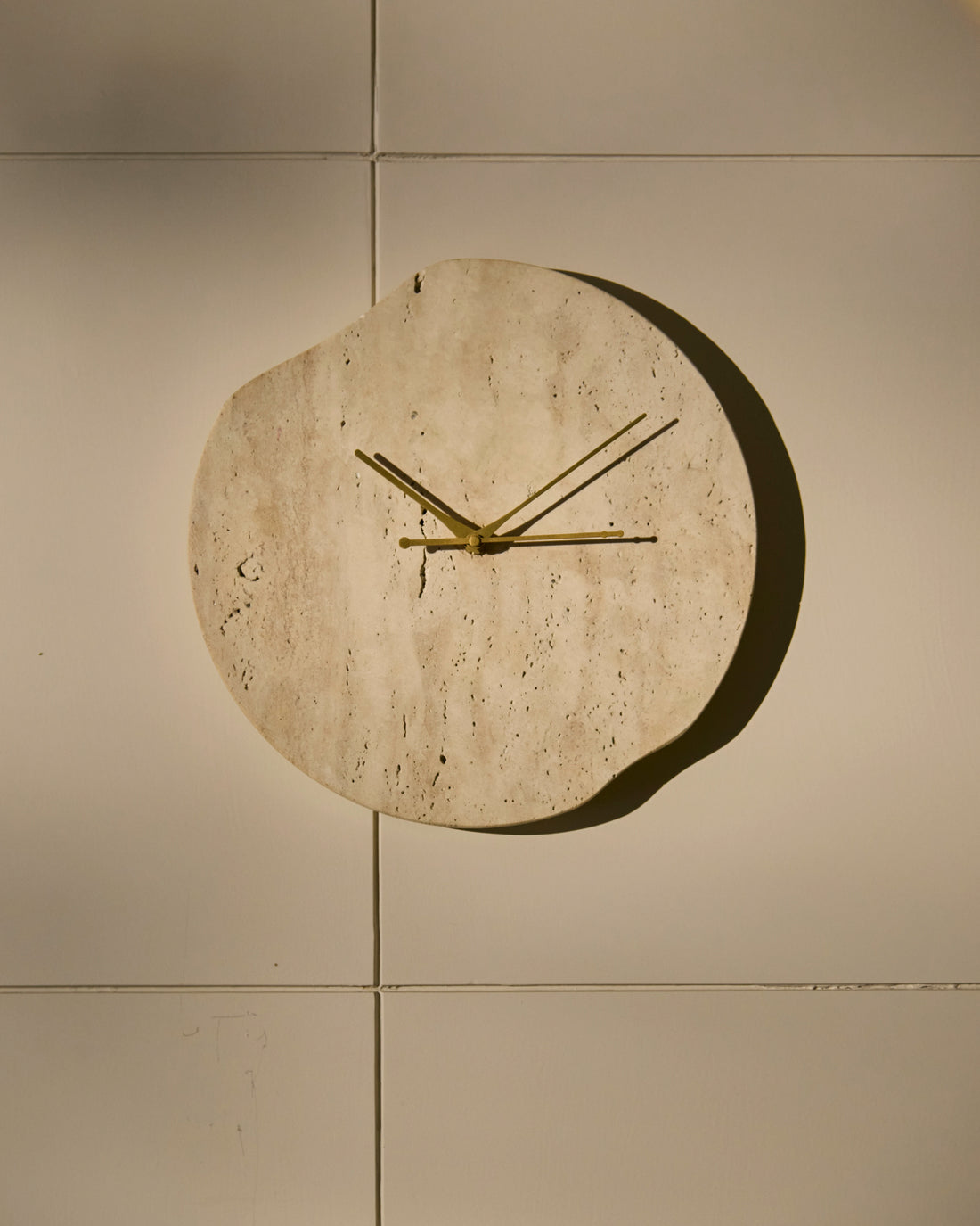 Handcrafted travertine wall clock with organic form and minimalist Golden hands