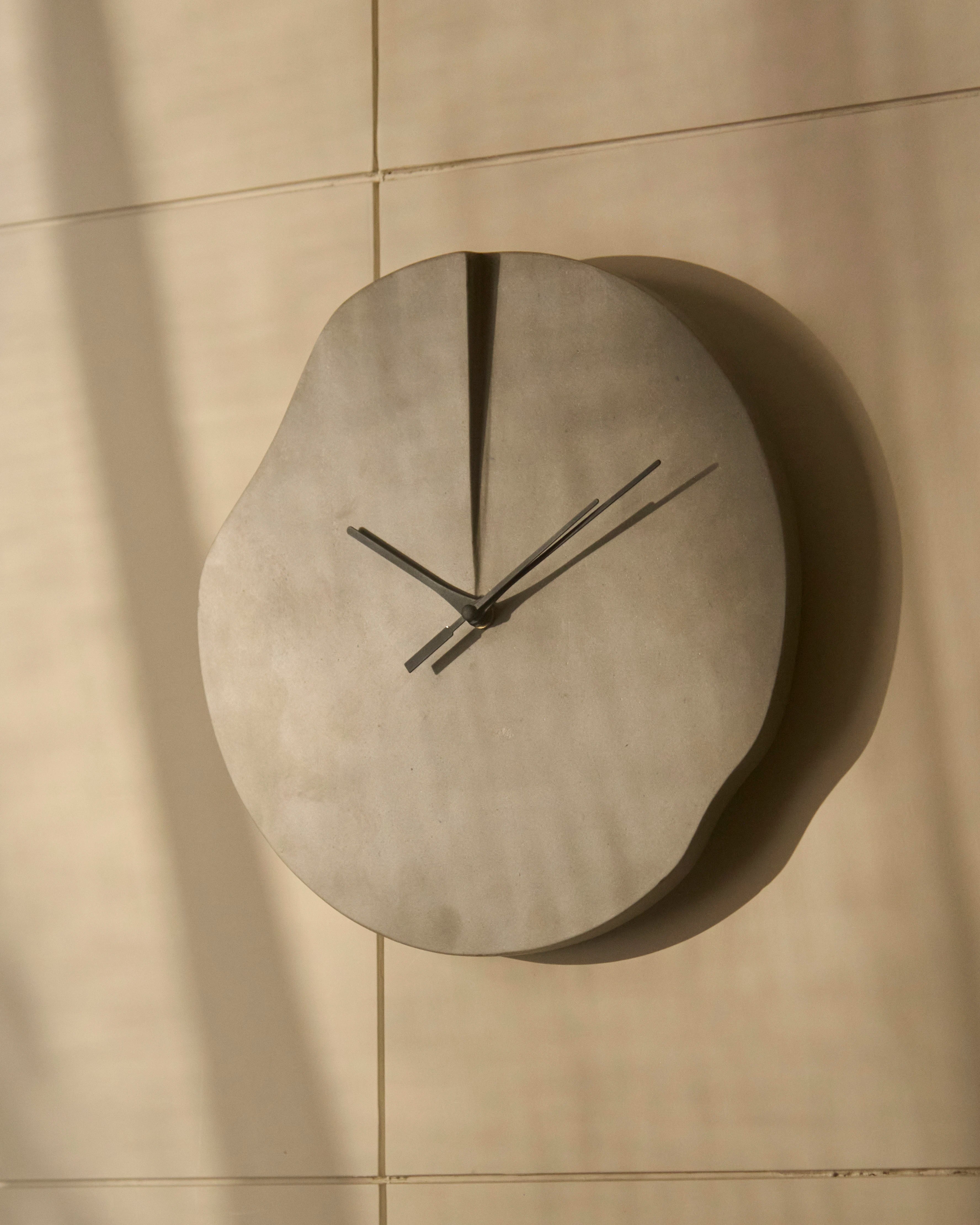 Modern sculptural wall clock with organic silhouette and minimalist black hands