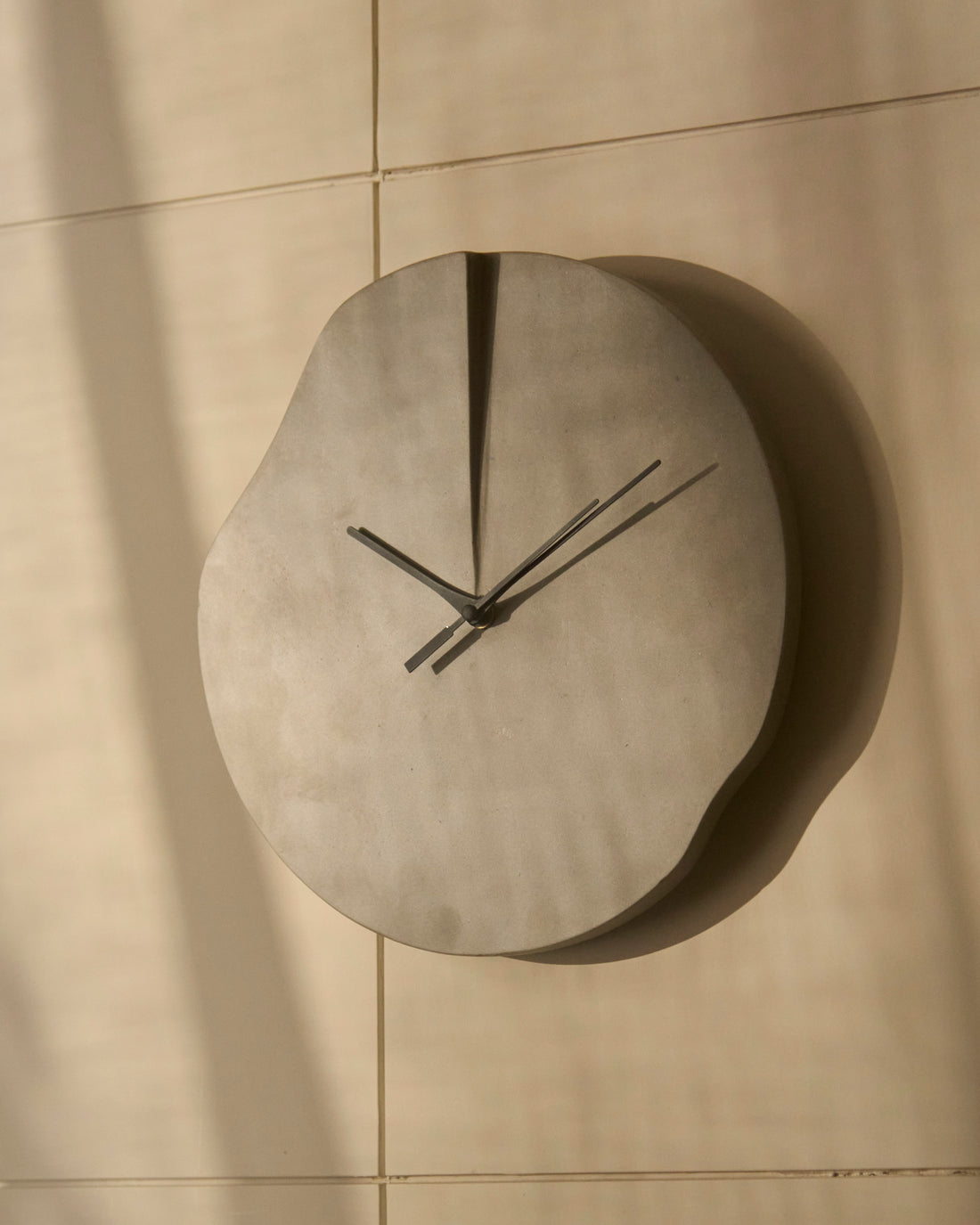 Modern sculptural wall clock with organic silhouette and minimalist black hands